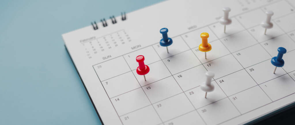 Embroidered red pins on a calendar event Planner calendar,clock to set timetable organize schedule,planning for business meeting or travel planning concept.